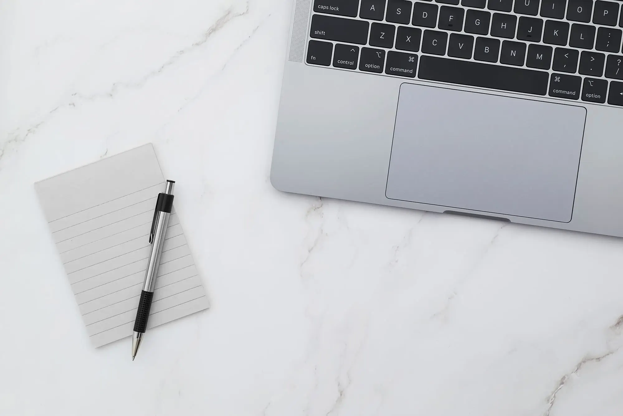 Laptop and notepad on a marble desk
